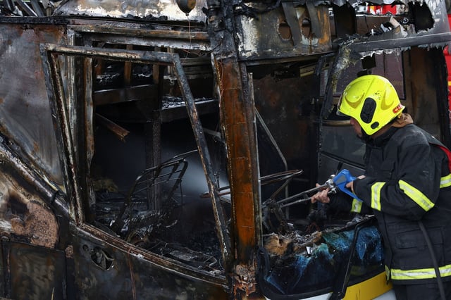 Firefighter works to extinguish a burning bus that was carrying teachers and students from Wat Khao Phraya school, reportedly killing almost a dozen, on the outskirts of Bangkok, Thailand, October 1, 2024. REUTERS/Chalinee Thirasupa
