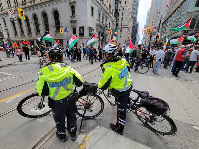 Police officers look on and block traffic as people take part in a pro-palestinian protest in Toronto on Saturday Sept. 7, 2024. THE CANADIAN PRESS/Doug Ives