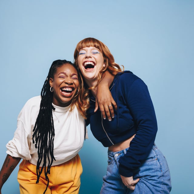Two interracial best friends laughing and having a good time together in a studio. The survey, whose respondents were mostly young women, found that friendship was most strongly associated with happiness, more than other factors they measured, including self-esteem, family relationships and personality traits.