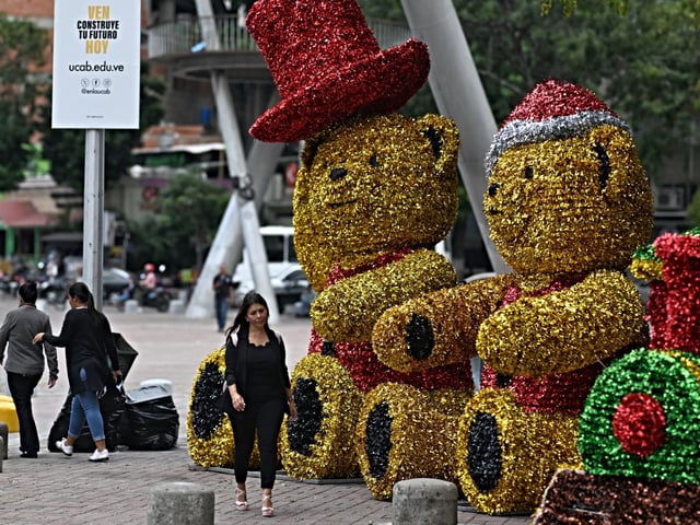 A woman walks past giant Christmas decorations in Caracas on October 1, 2024. Venezuelan President Nicolas Maduro declared on September 3 that Christmas will come early this year, on October 1, in his attempt to impart some holiday cheer following a disputed presidential election that the opposition claims he stole. (Photo by JUAN BARRETO / AFP)