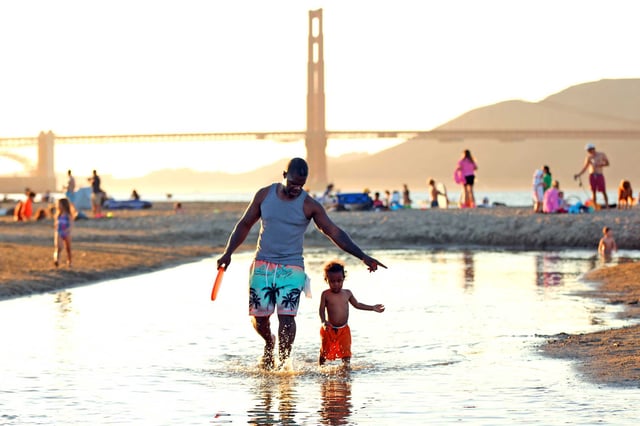 Douglas Williams leads his son, DJ, 2, through a pool of water at Crissy Field in San Francisco on Tuesday.