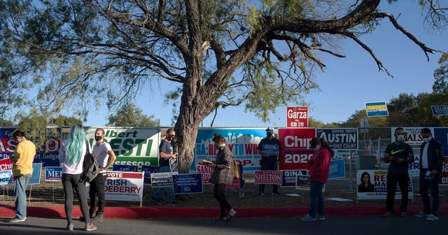 Voters wait in line outside Cody Public Library in San Antonio during the evening hours of Election Day, Oct. 23, 2020.