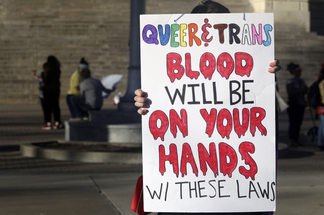 A protester outside the Kansas Statehouse holds a sign after a rally for transgender rights on the Transgender Day of Visibility, March 31, 2023, in Topeka, Kan. Kansas will no longer change transgender people's birth certificates to reflect their gender identities, the state health department said Friday, Sept. 15, 2023, citing a new law that prevents the state from legally recognizing those identities.