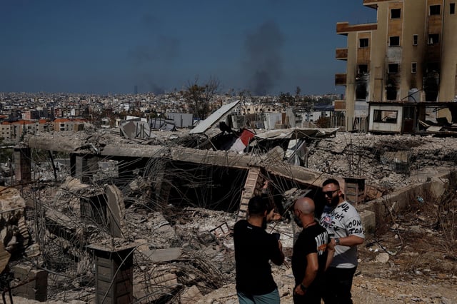 People stand amid damage caused by Israeli airstrikes, as smoke rises over Beirut southern suburbs, amid ongoing hostilities between Hezbollah and Israeli forces, in the Choueifat district, in Beirut, Lebanon, October 3, 2024.