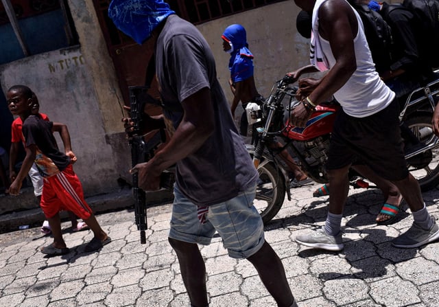 Children accompany armed gang members in a march organised by former police officer Jimmy "Barbecue" Cherizier, leader of an alliance of armed groups, in the Delmas neighbourhood, in Port-au-Prince, Haiti, May 10, 2024/REUTERS/Pedro Valtierra Anza/File Photo