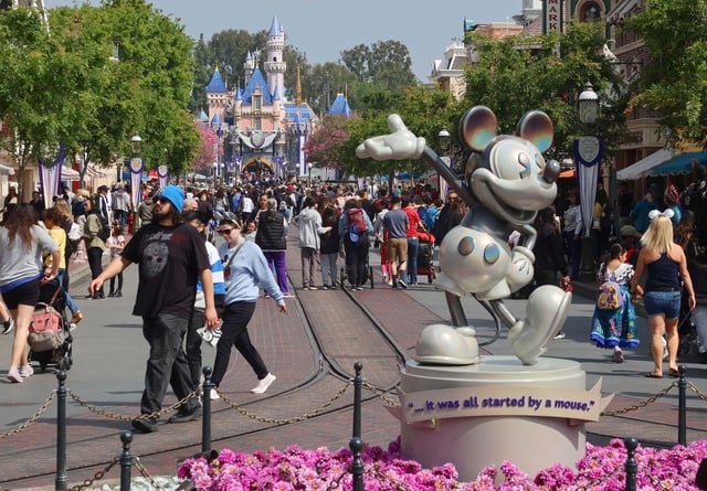 ANAHEIM, CA - APRIL 11: People walk next to Mickey Mouse along Main Street in front of the Sleeping Beauty Cast at the Disneyland theme park on April 11, 2023, in Anaheim, California. (Photo by Gary Hershorn/Getty Images)