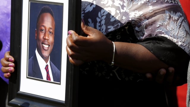 FILE - Caroline Ouko, mother of Irvo Otieno, holds a portrait of her son at the Dinwiddie Courthouse in Dinwiddie, Va., March 16, 2023. The family of Otieno, a man who died while handcuffed and pinned to the floor for about 11 minutes as he was being admitted to a Virginia psychiatric hospital, has reached an $8.5 million settlement, Wednesday, Sept. 20, 2023, with the state, county and the sheriff whose deputies were involved in restraining the man. (Daniel Sangjib Min/Richmond Times-Dispatch via AP, File)