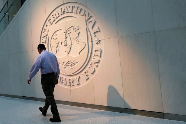 A man walks past the International Monetary Fund (IMF) logo at its headquarters in Washington, U.S., May 10, 2018. REUTERS/Yuri Gripas/File Photo