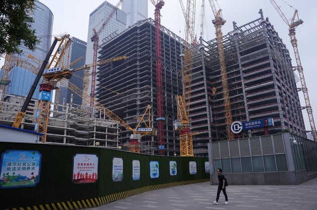 A person walks past a construction site in Beijing's Central Business District (CBD), China July 14, 2024. REUTERS/Tingshu Wang/File Photo