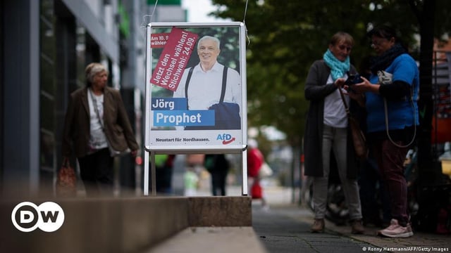 People walk past an election poster showing Jörg Prophet in Nordhausen