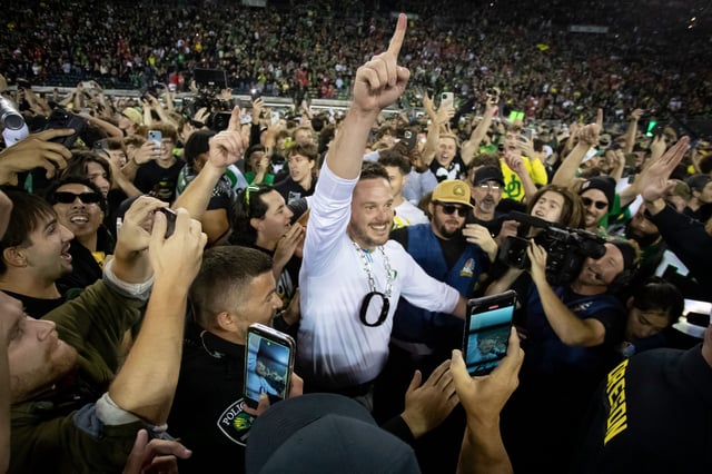 Coach Dan Lanning celebrates amid a crowd of fans on the field as No. 3 Oregon knocked off No. 2 Ohio State 32-31 on Saturday at Autzen Stadium in Eugene, Ore.
