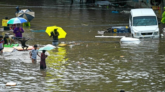 People wade through a flooded street amid heavy rainfall in Chennai on October 15, 2024. (Photo by R.Satish BABU / AFP)