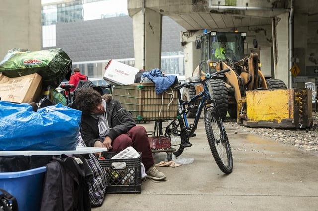 A person who experienced homelessness sits with their belongings as city workers move to clear an encampment on Toronto's Bay Street on May 15, 2020. 