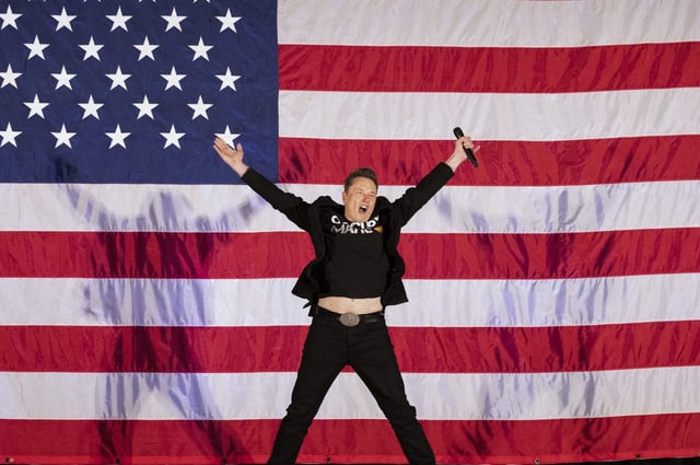 Tesla and SpaceX CEO Elon Musk jumps on stage as he arrives to speak at a town hall event hosted by America PAC in support of former US President and Republican presidential candidate Donald Trump at the Greater Philadelphia Expo Center in Oaks, Pennsylvania, on October 18, 2024.