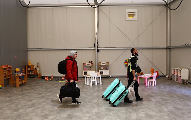 A security member helps to move the belongings of a family fleeing the Russian attack on Ukraine after their arrival at a temporary refugee shelter in Hanau, Germany, March 2, 2023.  REUTERS/Kai Pfaffenbach