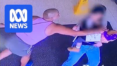 Still from CCTV of a woman in a pinkl singlet reaching out to a baby being held by its mother