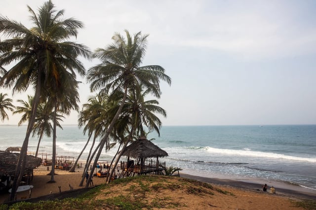 Thatched huts and palm trees stand on a beach in Arugam Bay, Sri Lanka.