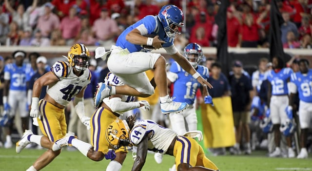 Mississippi quarterback Jaxson Dart, top, hurdles LSU safety Andre' Sam (14) during the second half of an NCAA college football game in Oxford, Miss., Saturday, Sept. 30, 2023. (AP Photo/Thomas Graning)