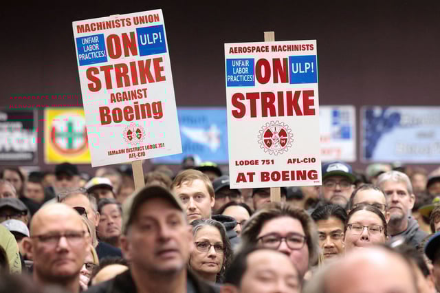 People hold signs during a strike rally for the International Association of Machinists and Aerospace Workers (IAM) at the Seattle Union Hall in Seattle, Washington, on October 15, 2024.