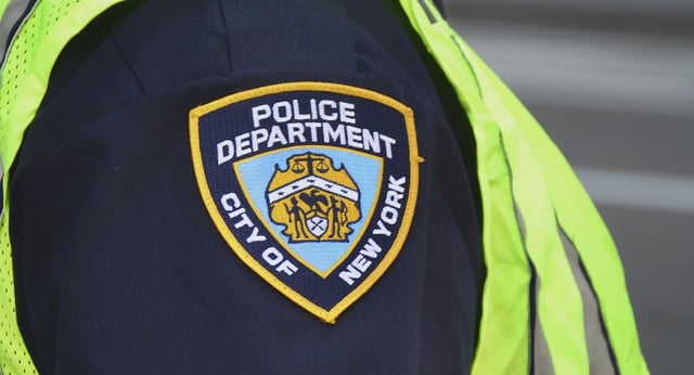 A New York City police officer stands at a busy street corner.