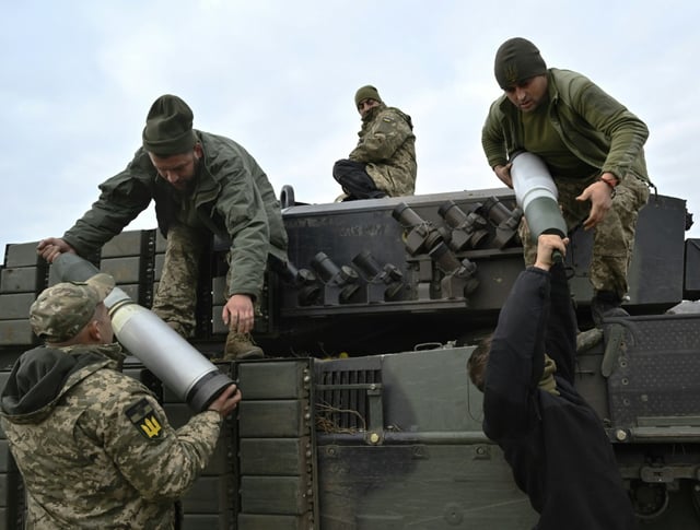 Servicemen from Ukraine's 33rd separate mechanized brigade load projectiles onto a Leopard 2A4 tank during training