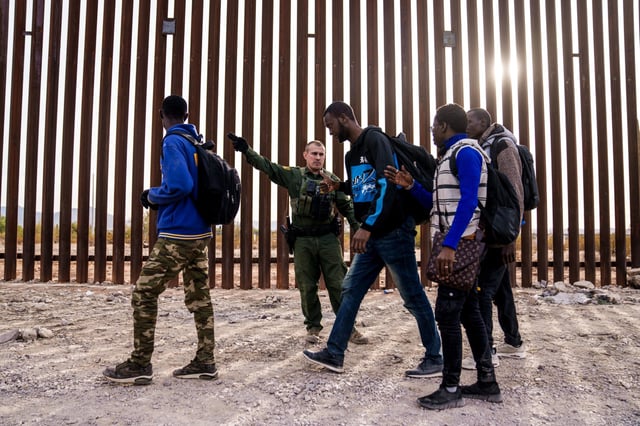 A U.S. Customs and Border Protection officer directs migrants at the U.S.-Mexico border in Lukeville, Ariz., on Dec. 11, 2023.