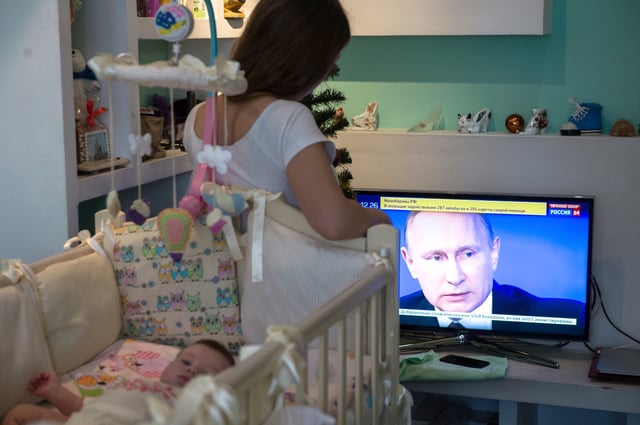 New Mother Watching Putin's Broadcast on TV