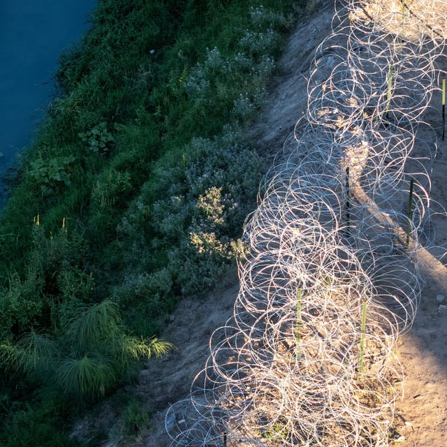 From an aerial view a Texas National Guard soldier inspects razor wire along the bank of the Rio Grande at the U.S.-Mexico border on September 18, 2024 in El Paso, Texas. A migrant who crossed illegally 25 years ago said he supported President-elect Donald Trump despite his plans for mass deportation.