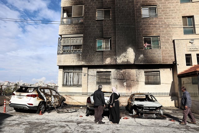 People inspect burnt cars and a building after a reported attack by Israeli settlers on the outskirts of Ramallah city in the occupied West Bank on November 4.