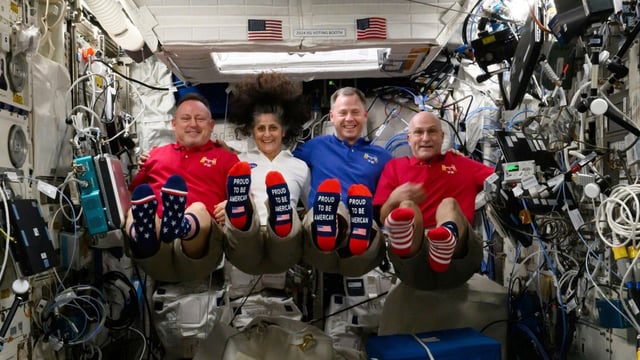In this photo provided by NASA, from left, astronauts Butch Wilmore, Suni Williams, Nick Hague and Don Pettit show their U.S. flag-themed socks aboard the International Space Station on Election Day, Tuesday, Nov. 5, 2024. 