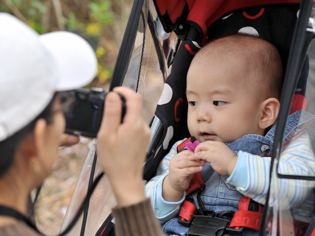 A South Korean woman takes a photo of her baby sitting on a pushchair during their family picnic in a downtown park in Seoul on April 13, 2009. After years of promoting family planning in the crowded nation of 48.6 million, South Korea in recent years has become increasingly alarmed at the prospect of an ageing society -- with a huge pensions bill and too few workers to sustain economic growth. (JUNG YEON-JE/AFP via Getty Images)