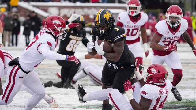 Missouri Tigers running back Marcus Carroll (No. 9) runs through the Arkansas Razorbacks’ defense during the regular-season college football finale for both teams at Faurot Field at Memorial Stadium in Columbia on Saturday, Nov 30, 2024.