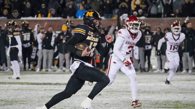 Missouri Tigers quarterback Brady Cook (12) runs in for the game-winning touchdown as Arkansas Razorbacks defensive back Doneiko Slaughter (3) looks on at Faurot Field at Memorial Stadium on Nov. 30, 2024.