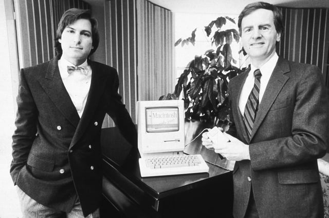 Former Apple executives Steve Jobs (left) and John Sculley (right) pose with a new Macintosh computer in January 1984.