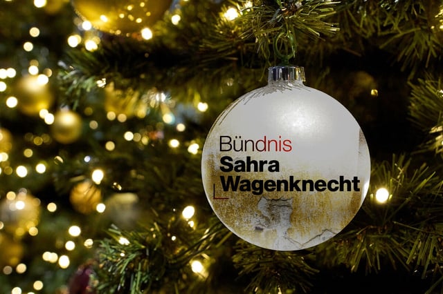 Eine weiße Christbaumkugel mit Aufschrift Sahra Wagenkneckt vor Tannengrün mit Lichterkette