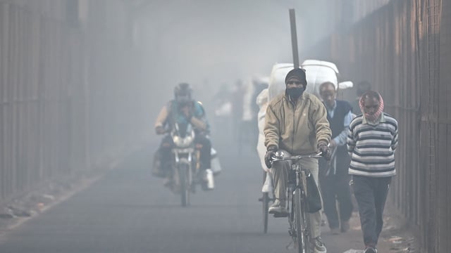 Commuters make their way through an old iron bridge on a smoggy winter morning in New Delhi on December 19, 2024. 