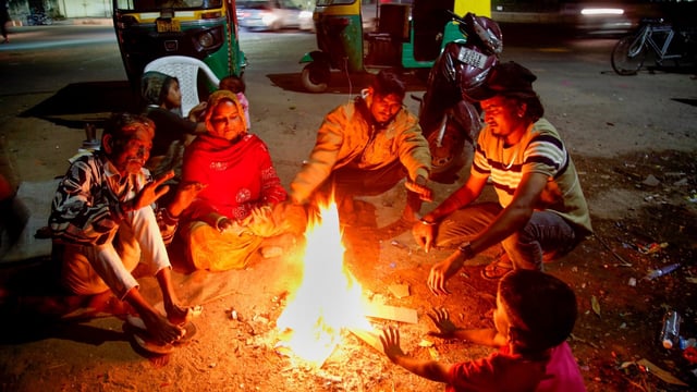 People getting warm themselves with bonfire during a cold wave