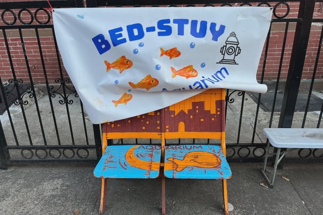 A sign that says "Bed-Stuy Aquarium" hangs above two chairs. But organizers say the fish have been relocated.