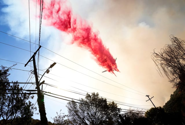 A DC-10 dumps fire retardant on Mandeville Canyon Road on Jan 11, 2025, during a battle to save the homes in the Brentwood community from the Palisades Fire that started on Jan. 7.