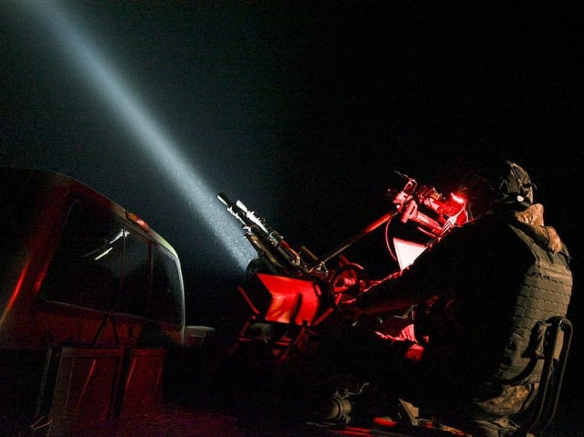 A Ukrainian serviceman of the mobile air defense unit sits behind an anti-UAV machine gun tracking Russian drones in the sky using a beam of light during night patrol on December 2, 2024 in Chernihiv Oblast, Ukraine.