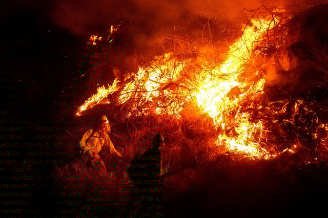 Firefighters battle the Lilac Fire along Interstate 15 near the Bonsall community of San Diego County, California, on Tuesday.