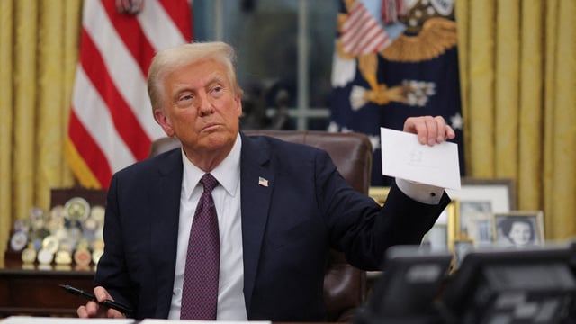 U.S. President Donald Trump holds former United States President Joe Biden's letter on the day he signs documents as he issues executive orders and pardons for January 6 defendants in the Oval Office at the White House on Inauguration Day in Washington, U.S., January 20, 2025. REUTERS/Carlos Barria