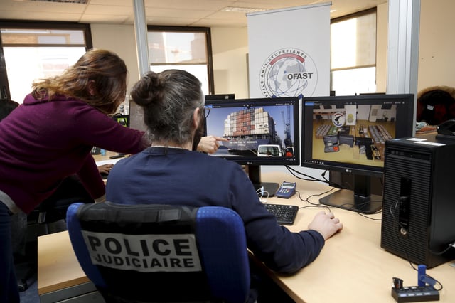 Des policiers regardent des photos d'une saisie de drogue sur un porte container dans les locaux de l’Office anti-stupéfiants, à Nanterre. 