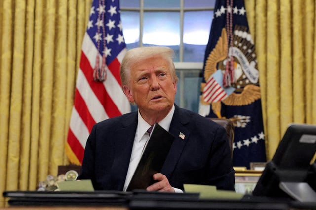 FILE PHOTO: U.S. President Donald Trump signs documents as he issues executive orders and pardons in the Oval Office at the White House on Inauguration Day in Washington, U.S., January 20, 2025. REUTERS/Carlos Barria/File Photo