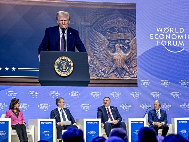 TotalEnergies chairman and CEO Patrick Pouyanne (2ndR) asks a question to US President Donald Trump (on screen) during his address by video conference at the World Economic Forum (WEF) annual meeting in Davos on January 23, 2025. (Photo by FABRICE COFFRINI / AFP)