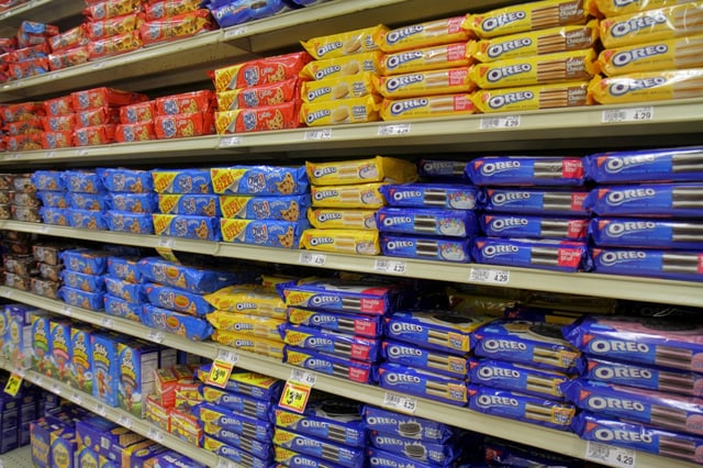 Various cookie brands are displayed on shelves at a grocery store.