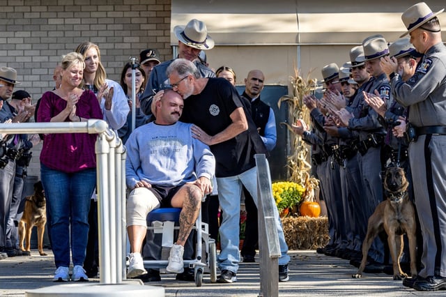New York State trooper Thomas Mascia gets a kiss from his father, Thomas, as he leaves in a wheelchair from Nassau University Medical Center in East Meadow, New York, on Nov. 1, 2024. 