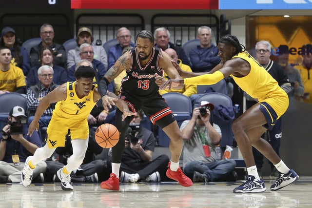 Houston forward J&#39;Wan Roberts (13) is defended by West Virginia guard Joseph Yesufu, left, and center Eduardo Andre during the first half of an NCAA college basketball game, Wednesday, Jan. 29, 2025, in Morgantown, W.Va. (AP Photo/Kathleen Batten)
