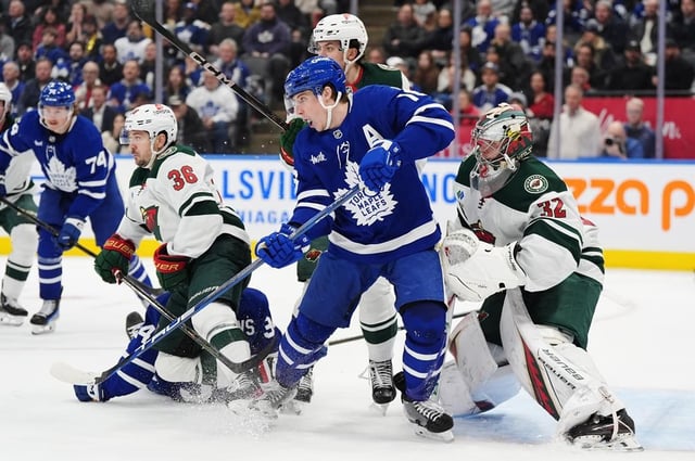 Toronto Maple Leafs' Mitch Marner (front centre) is checked as he screens Minnesota Wild goaltender Filip Gustavsson (32) during second period NHL hockey action in Toronto on Wednesday, January 29, 2025. THE CANADIAN PRESS/Frank Gunn