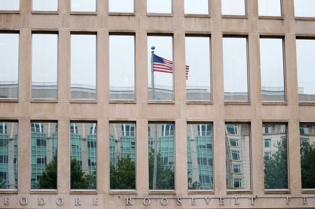 A U.S. flag is reflected in a window at the Theodore Roosevelt Federal Building, which houses the Office of Personnel Management headquarters, in Washington, DC., on June 5, 2015.